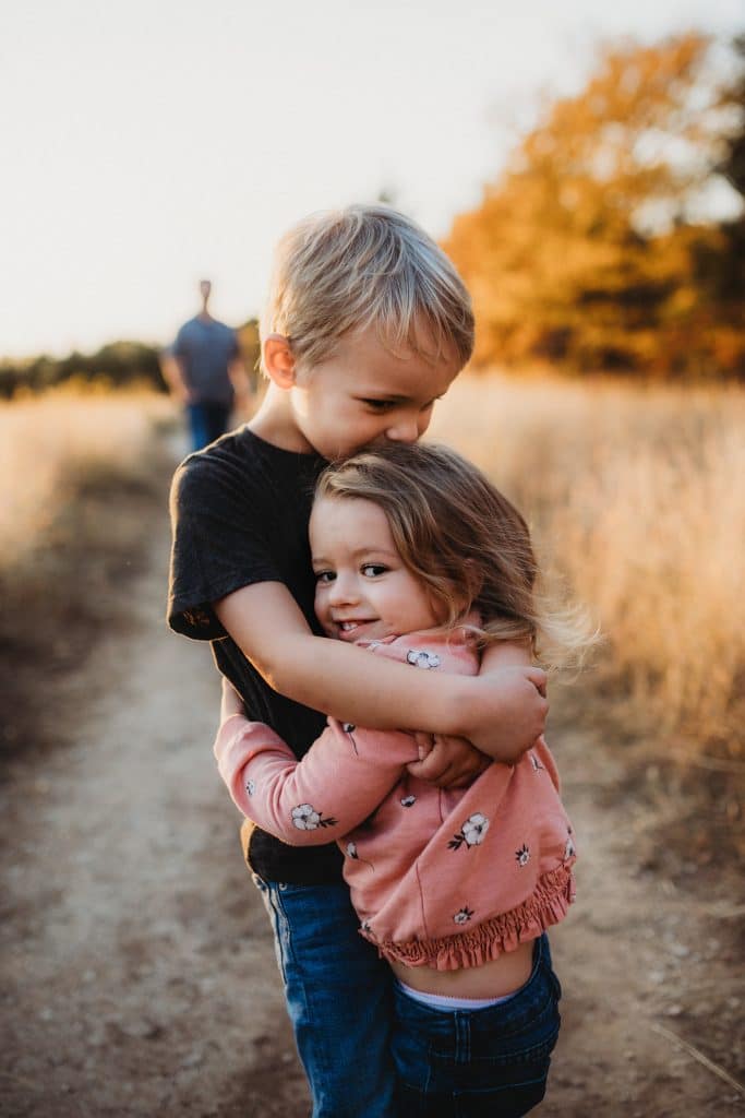 Young brother and sister hugging and smiling